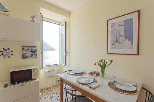 a kitchen with a table with chairs and a microwave at Il Timone by Rent All Como in Colonno