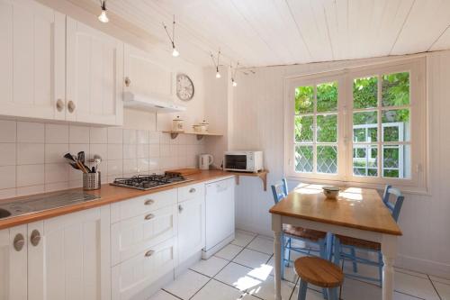 une cuisine avec des armoires blanches et une table en bois dans l'établissement Les Bleuets, à Saint-Malo