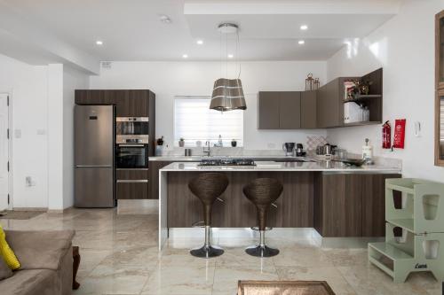 a kitchen with a large island with bar stools at Family-Friendly Spacious Townhouse with Garden - Close to Airport in Gudja
