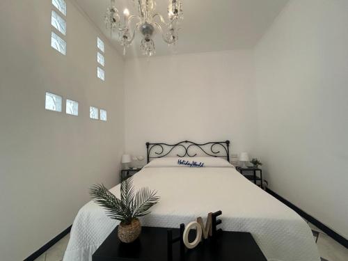1 dormitorio blanco con 1 cama con lámpara de araña en Il Cielo Con Un Dito by Holiday World, en Savona