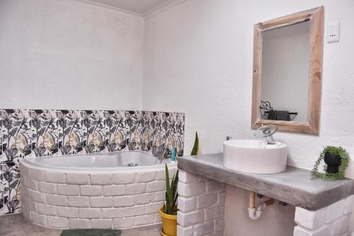 a bathroom with a tub and a sink and a mirror at Knowhere Selfcatering Unit 2 in Omaruru