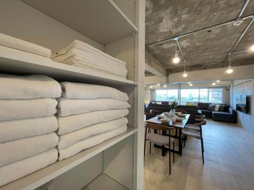 a room filled with stacks of towels and a dining room at bHOTEL Dai3Himawari - 30 sec to PeacePark!! HUGE comfort house Up to 10p in Hiroshima