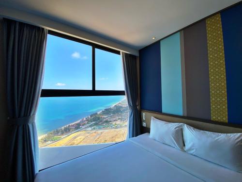 a bedroom with a bed and a large window at Apec Mandala Mũi Né Resorts & Hotels NN in Phan Thiet