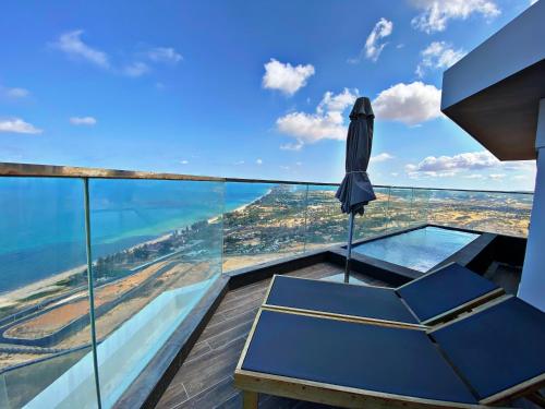 an umbrella and a chair on a balcony with the ocean at Apec Mandala Mũi Né Resorts & Hotels NN in Phan Thiet