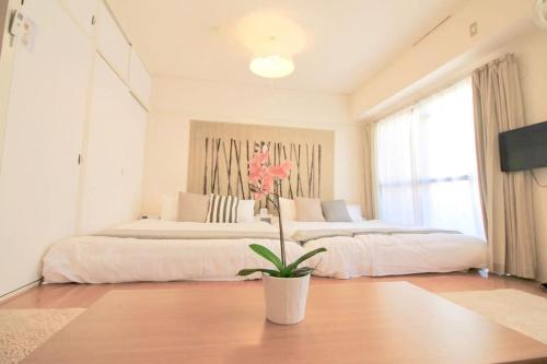 a bedroom with two beds and a potted plant at Earls Court by b hotel - Spacious & Relaxing just 4 blocks to Peace Park in Hiroshima