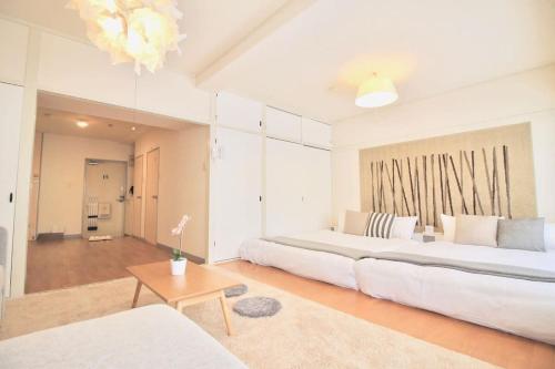 een grote witte slaapkamer met een groot bed en een tafel bij Earls Court - Capacious & Relaxing just 4 blocks to Peace Park in Hiroshima