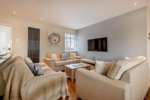 a living room with two couches and a flat screen tv at Oakwood Bungalow Christchurch Sleeps 8 in Iford