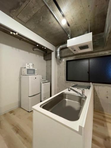 a kitchen with a sink and a refrigerator at b hotel M's lea - 2BR Modern Apartment next to Peace Park 10 Ppl in Hiroshima