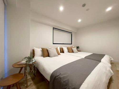 a large white bed in a room with a picture at bHOTEL M's lea - 2BR Modern Apartment next to Peace Park 10 Ppl in Hiroshima