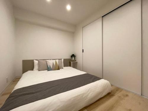 a bedroom with a large bed with white walls at b hotel M's lea - 2BR Modern Apartment next to Peace Park 10 Ppl in Hiroshima