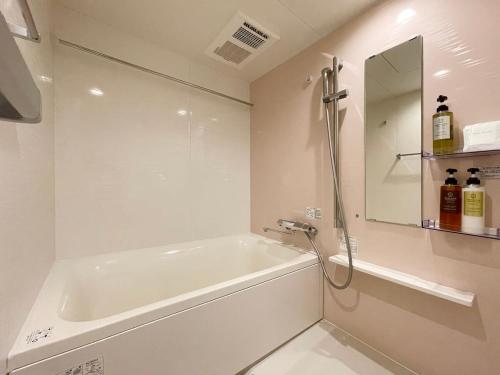 a white bathroom with a tub and a mirror at b hotel M's lea - 2BR Modern Apartment next to Peace Park 10 Ppl in Hiroshima