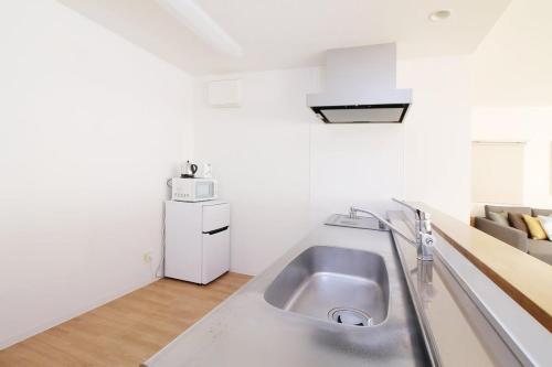uma cozinha com um lavatório de aço inoxidável num quarto em bHOTEL Marumasa - Large 2BR Apt 10PPL near Peace Park 301 em Hiroshima