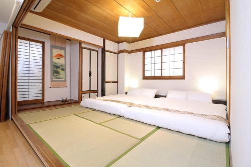 um quarto com uma cama grande num quarto com janelas em bHOTEL Marumasa - Large 2BR Apt 10PPL near Peace Park 301 em Hiroshima