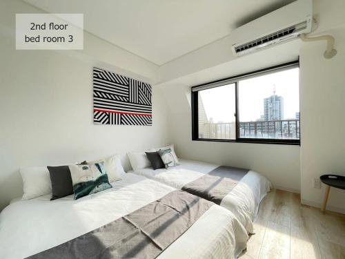 1 dormitorio con 1 cama blanca grande y ventana en bHOTEL M's lea - Spacious 2 level apartment 4BR for 16 PPL, en Hiroshima