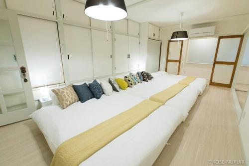 a large white couch with many pillows on it at bHOTEL Marumasa - Spacious next to PeacePark Family Condo Up to 13 P in Hiroshima