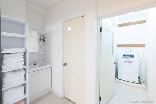 a white laundry room with a glass door and white cabinets at bHOTEL Marumasa - Spacious next to PeacePark Family Condo Up to 13 P in Hiroshima