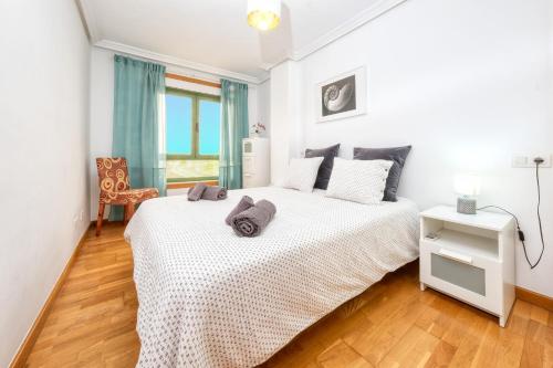 a bedroom with a large white bed and a chair at El Reducto Beach-first line of the sea in Arrecife