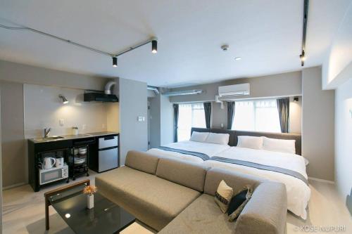 een slaapkamer met een groot bed en een bank bij bHOTEL Origaminn 401 - 5 mins Peace Park in Hiroshima