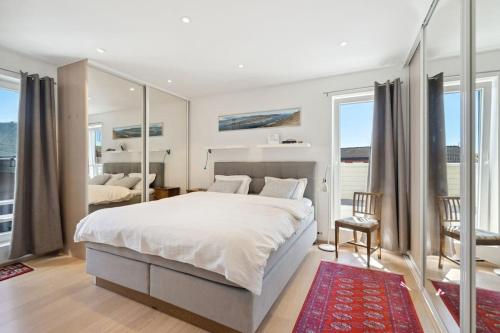 1 dormitorio con 1 cama blanca grande y espejo en Villa med fantastisk utsikt., en Tromsø