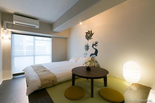 a bedroom with a large bed and a table at Origaminn 403 by b hotel - 5 mins PeacePark in Hiroshima