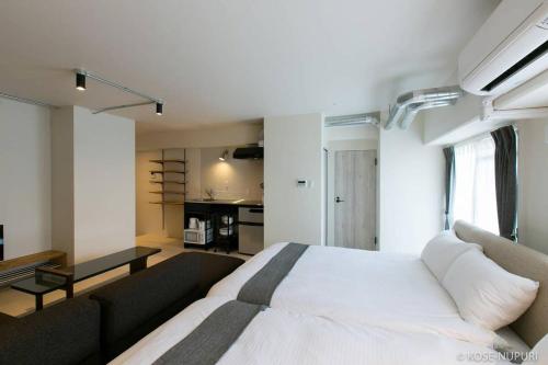 a bedroom with a large white bed and a couch at bHOTEL Origaminn 501 - 5 mins PeacePark in Hiroshima