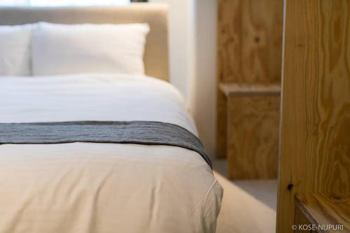 een slaapkamer met een bed met witte lakens en kussens bij Origaminn 502 by b hotel - 5 mins PeacePark in Hiroshima