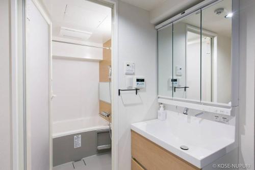 Baño blanco con lavabo y espejo en bHOTEL Origaminn 502 - 5 mins PeacePark en Hiroshima