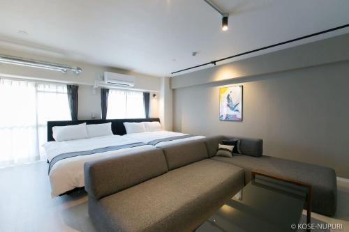 een slaapkamer met een groot bed en een bank bij bHOTEL Origaminn 601 - 5 mins PeacePark in Hiroshima