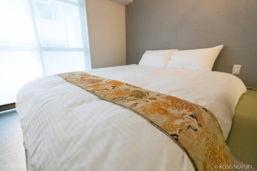 a bedroom with a white bed with a blanket on it at Origaminn 503 by b hotel - 5 mins PeacePark in Hiroshima