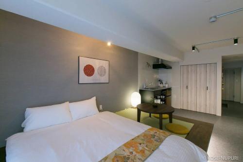 a bedroom with a white bed and a kitchen at bHOTEL Origaminn 503 - 5 mins PeacePark in Hiroshima