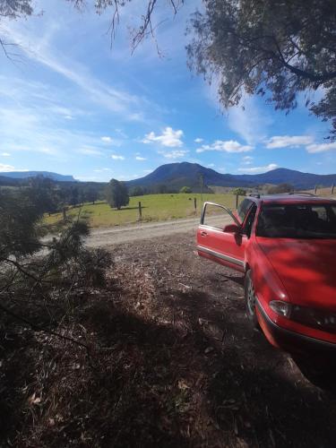 a red truck parked on the side of a dirt road at The Blue House in Nimbin