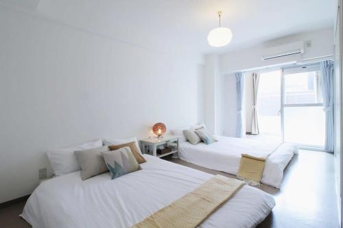 2 camas en una habitación blanca con ventana en bHOTEL La-Shante - 5 mins walk to the PeacePark & 2BR 10 ppl #101, en Hiroshima
