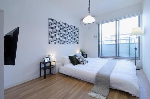 a white bedroom with a bed and a large window at b hotel Ball Park - 2mins walk Baseball 5mins walk Hiroshima Sta in Hiroshima