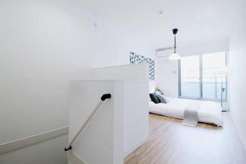 een witte slaapkamer met een bed en een groot raam bij b hotel Ball Park - 2mins walk Baseball 5mins walk Hiroshima Sta in Hiroshima