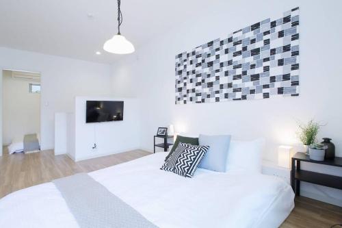 een slaapkamer met een wit bed en een tv bij b hotel Ball Park - 2mins walk Baseball 5mins walk Hiroshima Sta in Hiroshima