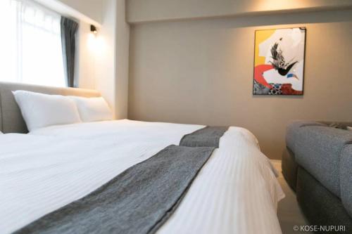広島市にあるOrigaminn 701 by b hotel - 5 mins PeaceParkのベッドルーム(白いベッド、毛布付)