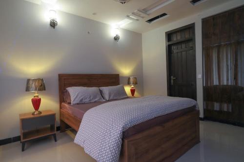 a bedroom with a bed and two lamps and a door at Vista Valle in Murree