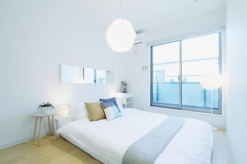 a white bedroom with a bed and a large window at b hotel Ball Park - Apt 2mins to Baseball 5mins to Hiroshima Sta in Hiroshima