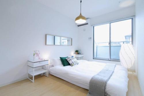 a white bedroom with a bed and a large window at b hotel Ball Park - NewlyBuild 2 bedrm Apt 2 mins Baseball Museum 4ppl in Hiroshima