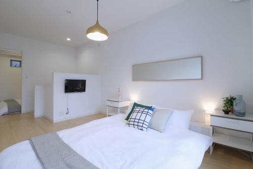 a white bedroom with a bed and a tv at b hotel Ball Park - NewlyBuild 2 bedrm Apt 2 mins Baseball Museum 4ppl in Hiroshima