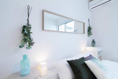 een spiegel aan een witte muur boven een witte bank bij b hotel Ball Park - 2mins walk Baseball 5mins walk Hiroshima Sta 4ppl in Hiroshima