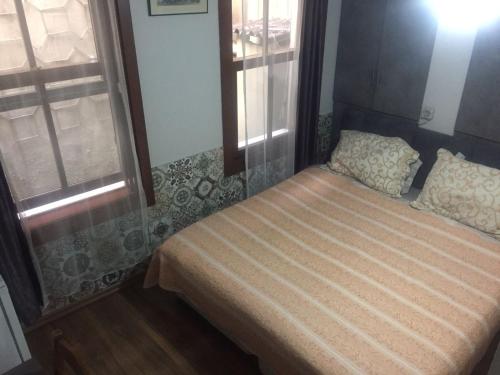 a small bed in a room with two windows at Galata Life Istanbul in Istanbul