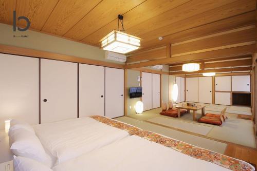 a bedroom with a large white bed and a living room at Hanagin by b hotel - 3 Bedroom Japanese apartment for 11 people 201 in Hiroshima