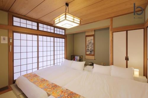 a large white bed in a room with windows at Hanagin by b hotel - 3 Bedroom Japanese apartment for 11 people 201 in Hiroshima