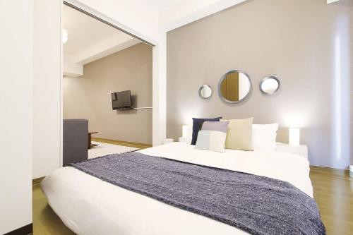 Un dormitorio con una gran cama blanca y espejos en bHotel 560 Comfy Elegant 1BR apartment for 4 people, en Hiroshima