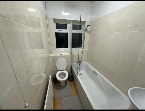 a bathroom with a toilet and a tub and a sink at Queenel Room in Eltham