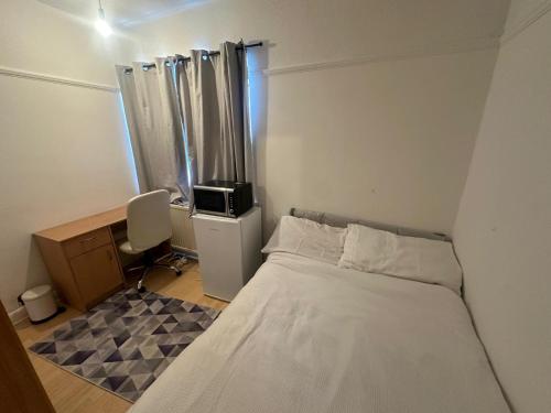 a small bedroom with a bed and a desk at Queenel Room in Eltham