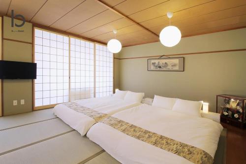 ein großes weißes Bett in einem Zimmer mit Fenstern in der Unterkunft Hanagin by b hotel - Large 2 bedroom apartment for 12people 301 in Hiroshima