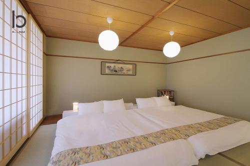a bedroom with a large white bed with two lights at Hanagin by b hotel - Large 2 bedroom apartment for 12people 301 in Hiroshima