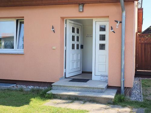 a white door on a pink house with stairs at Ferienhaus Moewe in Hanshagen